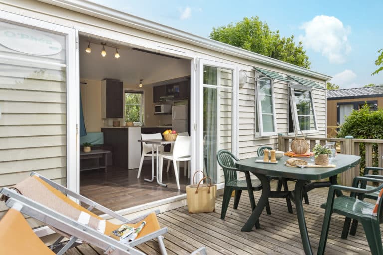 Mobil-home avec terrasse et mobilier extérieur.