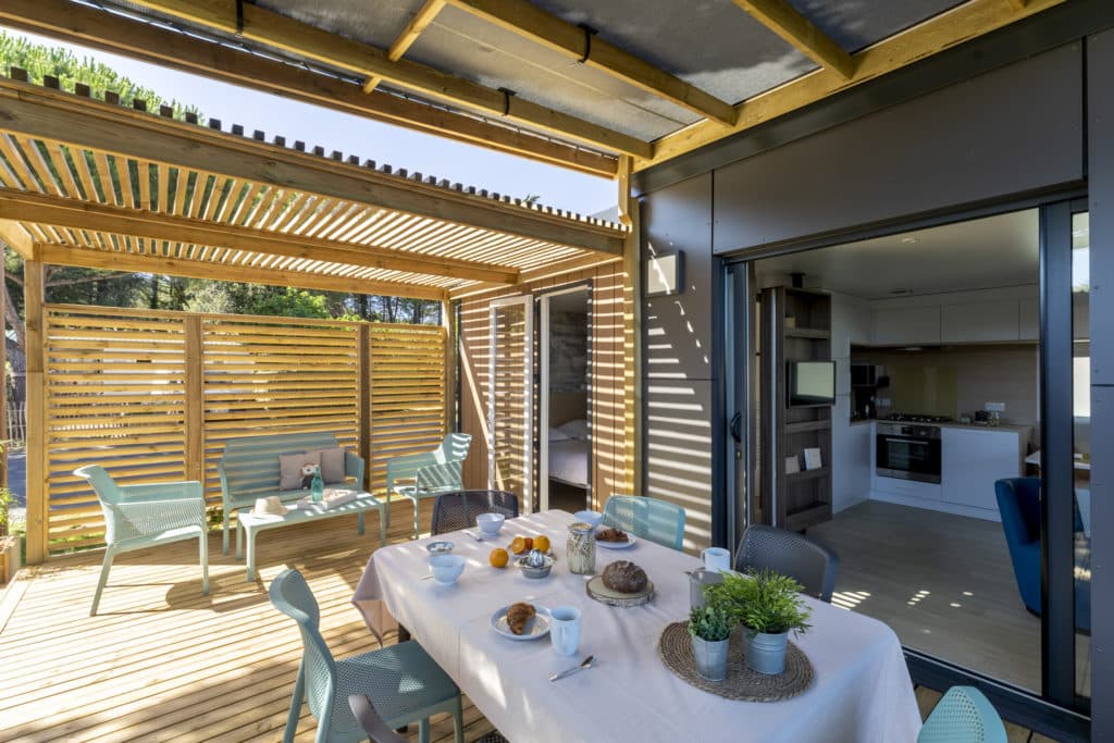 Terrasse ensoleillée avec table dressée et cuisine moderne.