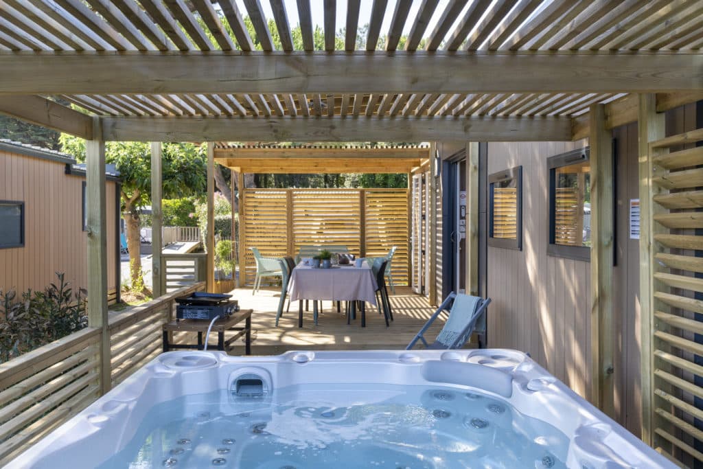 Terrasse avec jacuzzi et salle à manger extérieure.