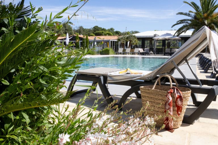 Piscine extérieure avec transats et palmiers.