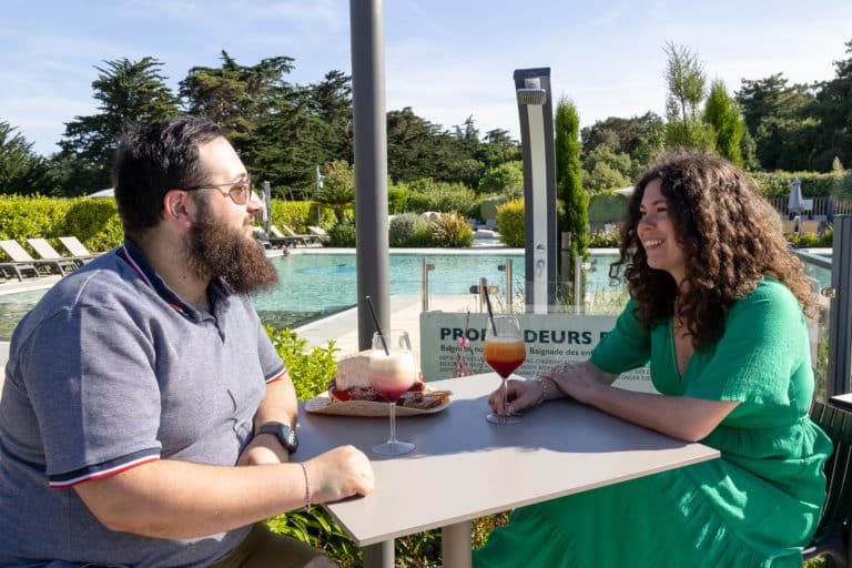 Deux personnes buvant des cocktails près d'une piscine.