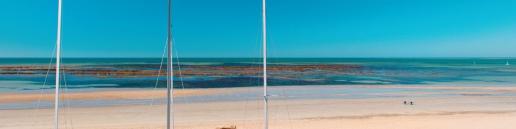 Plage sereine avec horizon turquoise et voiliers.